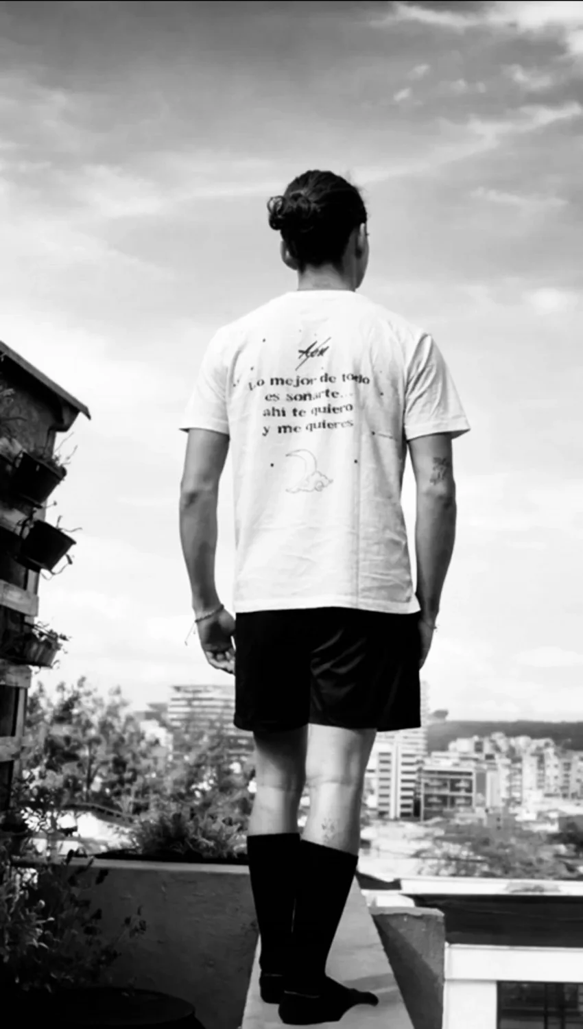 Espalda de la camiseta Soñarte puesta, mirando la ciudad desde una azotea